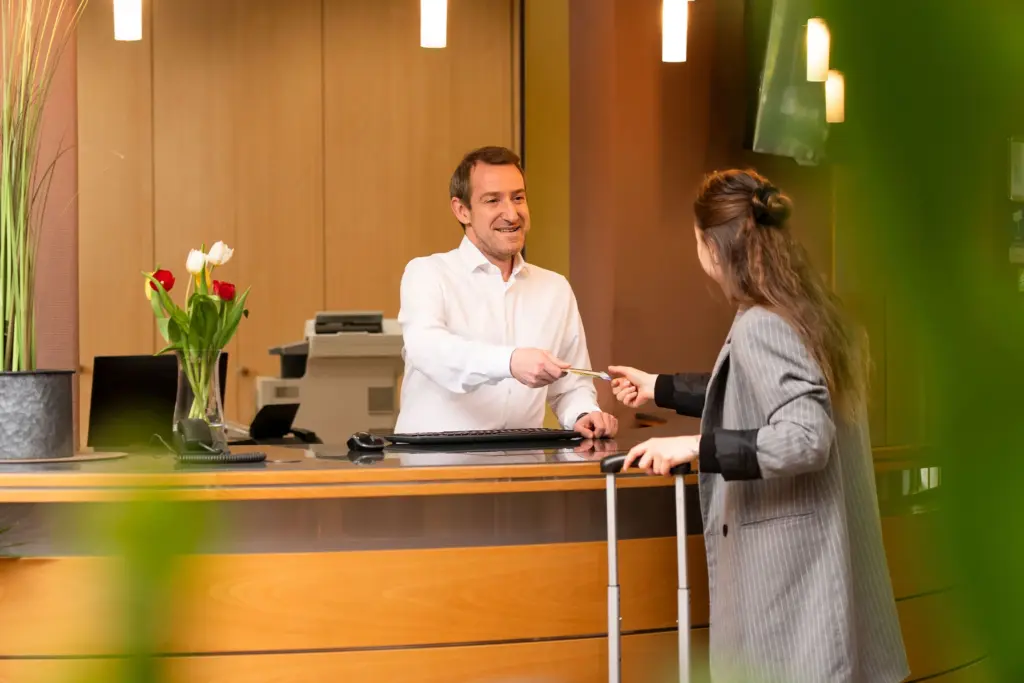 Rezeptionist überreicht einem Gast die Zimmerkarte