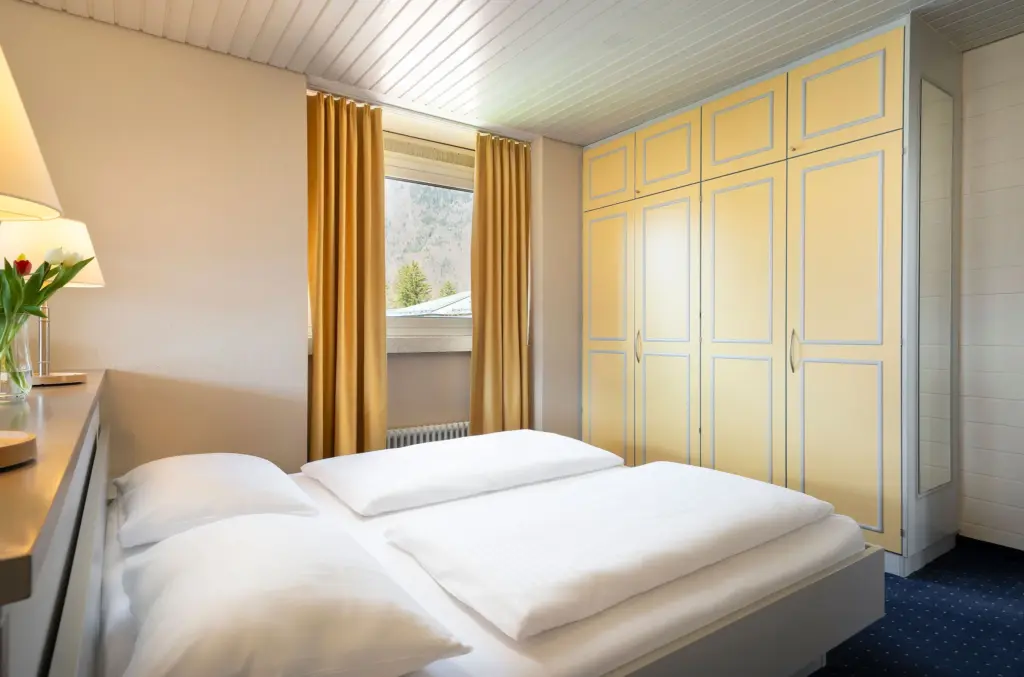 Hotelzimmer mit Doppelbett und blauem Teppich